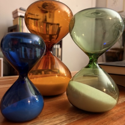 Set of three hourglasses of different sizes. One is cobalt blue, another amber, and another sage green.