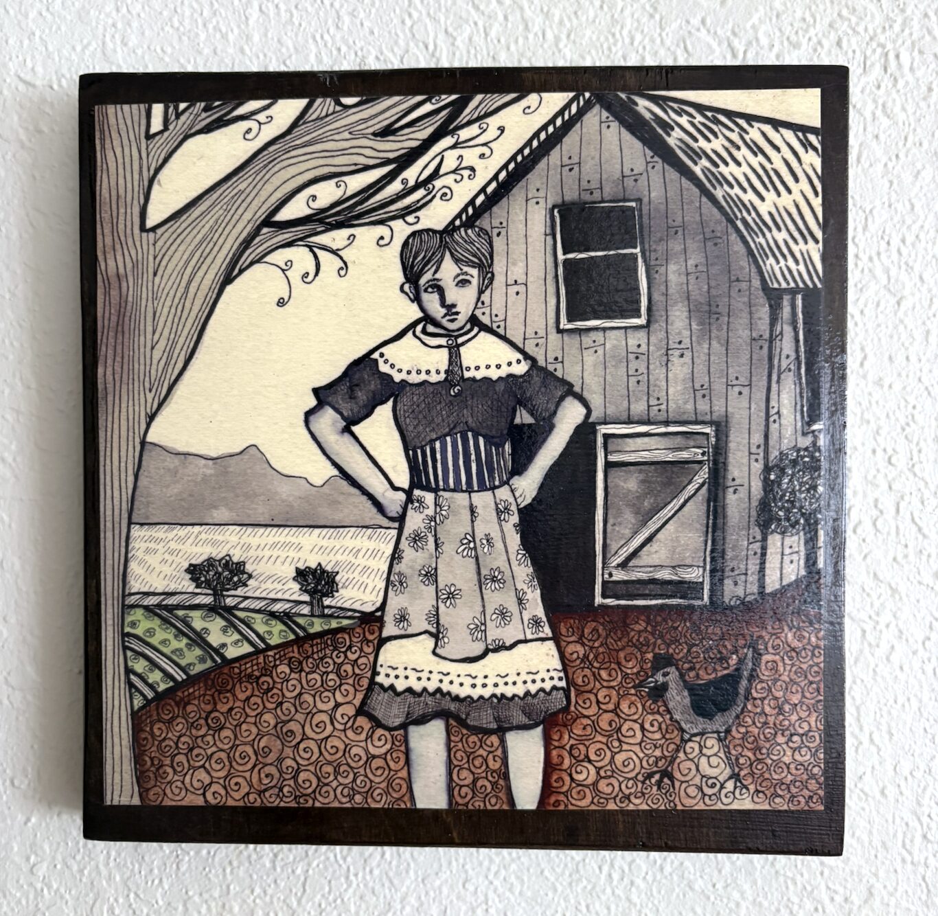 Photo of a piece of art showing a person wearing a dress and standing in front of a barn, next to a tree, with open farmland behind them and hills in the distance. A chicken is walking next to them.